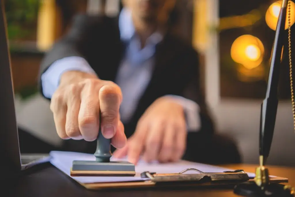 close up of a person s hand stamping with approved stamp on approval certificate