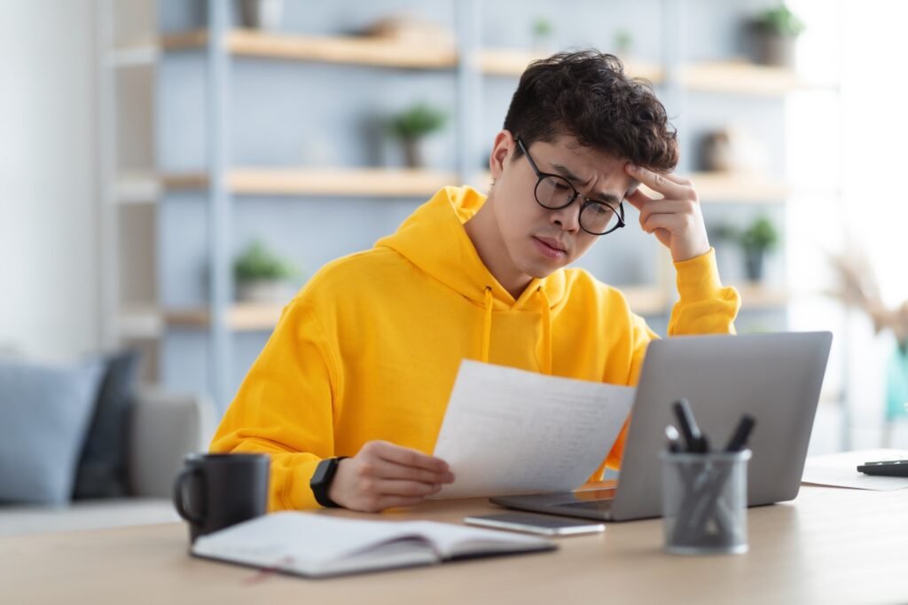 man holding paper reading report working on pc at home