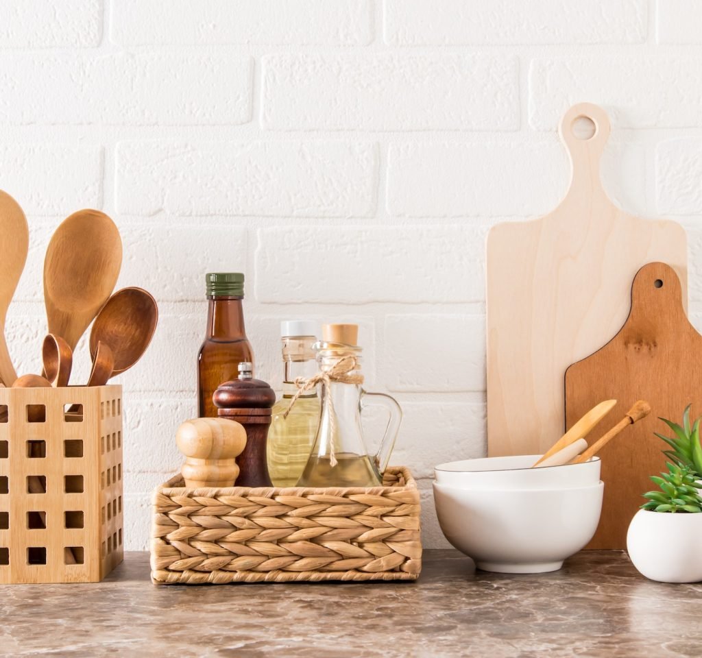 stylish white kitchen background with kitchen utensils and green potted house plants on a marble cou